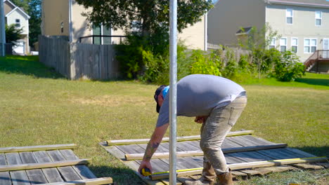 Worker-uses-tape-measure-before-repairing-broken-fence