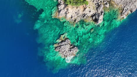 Sunlit-cliffs-on-corfu-island-in-the-ionic-sea,-showcasing-vibrant-blue-waters,-aerial-view