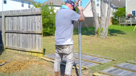 Following-worker-set-metal-post-in-ground