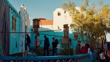 Foreign-tourists-enter-colorful-Nubian-house,-Nubian-village,-Aswan,-Egypt