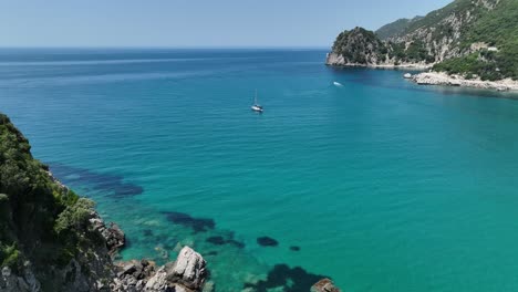 Ein-Segelboot-Auf-Klarem,-Blauem-Wasser-Nahe-Der-Küste-Der-Insel-Korfu,-Sonniger-Tag,-Luftaufnahme