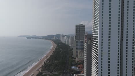 A-mesmerizing-aerial-perspective-of-Nha-Trang,-where-the-city's-skyline-is-kissed-by-clouds,-creating-a-dreamlike-atmosphere-as-traffic-flows-serenely-through-its-streets