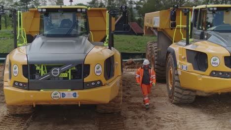 PPe-laden-construction-worker-inspects-a-fleet-of-dump-trucks-on-a-construction-site