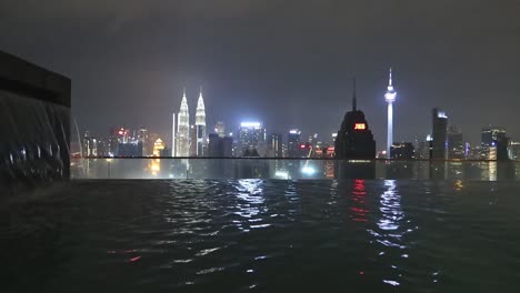 Luxury-Infinity-Pool-on-Skyscraper-rooftop-overlooking-City-Skyline-at-Night,-Kuala-Lumpur