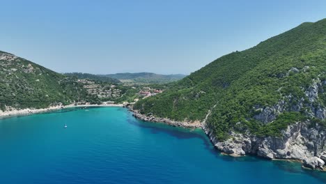 Playa-De-Liapades-En-Corfú,-Grecia,-Mostrando-Aguas-Azules-Y-Una-Costa-Escarpada,-Mediodía,-Vista-Aérea