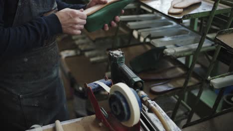 Craftsman-buffs-sole-of-a-sandal-on-machinery-in-workshop