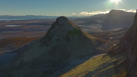 Flying-close-past-crumbling-cliff-edge-towards-isolated-landslip-peak-with-sunstar-reveal