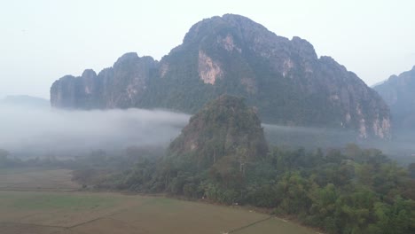 Drohnenschuss-Auf-Nebelverhangene-Klippen-In-Vang-Vieng,-Der-Abenteuerhauptstadt-Von-Laos