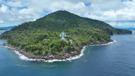 üppig-Grüne-Weh-Insel-Mit-Dem-Ikonischen-Kilometer-Nol-Denkmal,-Umgeben-Von-Blauem-Wasser,-Luftaufnahme