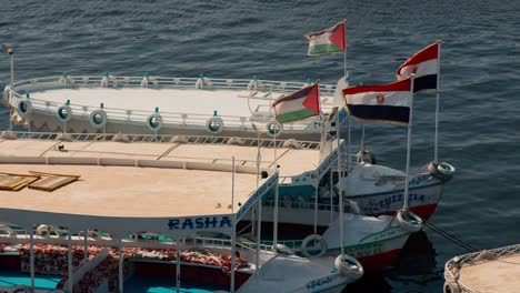 Egyptian-flag-on-boat-cruising-the-the-Aswan-Dam-and-Lake-Nasser,-Egypt-carrying-tourist-to-visit-the-Philae-temple-complex-island