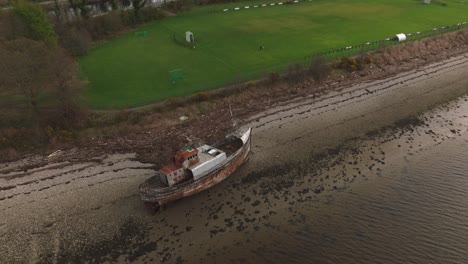 High-orbiting-shot-of-the-famous-Corpach-Shipwreck-landmark-on-a-beach