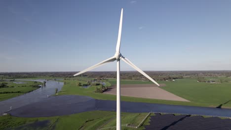 Slow-aerial-pan-showing-wind-turbine-and-solar-panels-in-The-Netherlands-with-Twentekanaal-meeting-river-IJssel-in-the-background