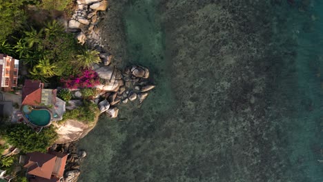 Top-down-view-of-beautiful-island-resort-on-cliff-next-to-ocean