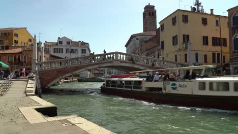 Boat-Filled-with-Tourists-Passes-Stone-Bridge-Built-Above-Venice-Grand-Canal