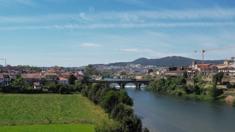 Aerial-view-of-Barcelos,-Portugal-showcasing-its-scenic-river-and-medieval-bridge-under-a-clear-sky