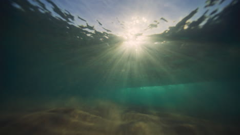 Sparkling-ray-of-light-underwater-in-middle-as-wave-breaks