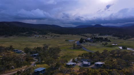 Dunkle-Gewitterwolken-über-Den-Bergketten-Des-Kosciuszko-Nationalparks-Mit-Der-Stadt-Crakenback-Im-Vordergrund,-New-South-Wales,-Australien