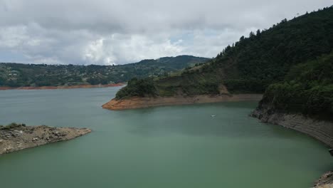 Agua-Turquesa-Aérea-En-Un-Lago-De-Montaña-Con-árboles-Y-Rocas