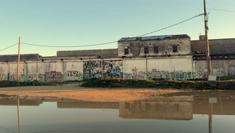 Tracking-shot-along-a-wall-decorated-with-murals-running-over-a-canal
