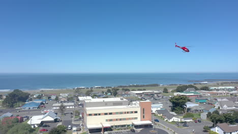 Drohnenaufnahme-Eines-Medizinischen-Rettungshubschraubers-Von-Cal-Ore-Life-Flight,-Der-Vom-Krankenhaus-Abhebt-Und-über-Gold-Beach,-Oregon,-USA,-Davonfliegt