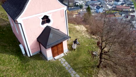 African-Tourist,-overlooked-by-a-drone-on-Kalvarienberg-overlooking-Traunsee-lake-in-Ebensee,-Salzkammergut-region,-serene-mountain-backdrop