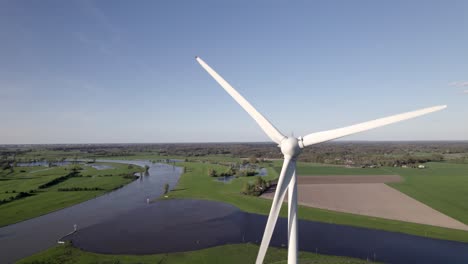 Slowly-turning-wind-turbine-in-The-Netherlands-with-Twentekanaal-meeting-river-IJssel-in-the-background