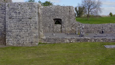Aerial-pullback-from-within-Annaghdown-Abbey-to-entrance,-revealing-ruin-details