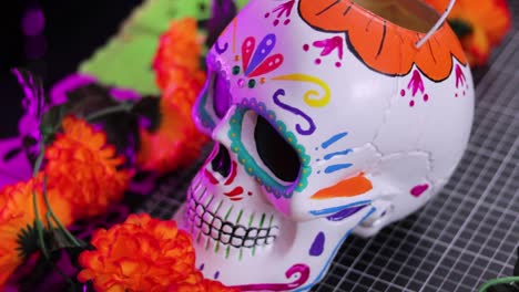 Colorful-Day-of-the-Dead-skull-decoration-among-vibrant-flowers,-close-up