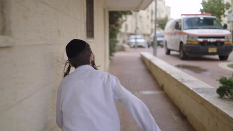 orthodox-jewish-boy-runing-in-the-street-in-isreal,-back-view