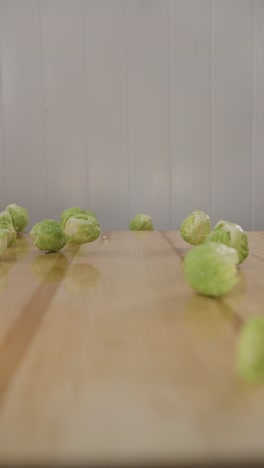 macro-food-close-up-Brussels-sprouts-falling-on-to-wooden-table-,-organic-green-vegetable-diet