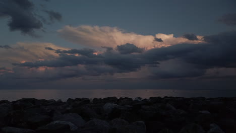 Stormy,-moody-sky-over-Lake-Ontario,-with-rocky-shoreline-and-boaters-in-the-distance