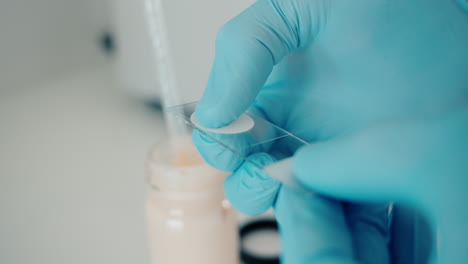 A-laboratory-technician-prepares-a-substance-for-analysis,-crushing-a-white-substance-between-two-glass-plates