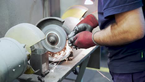 Worker-sharpens-metal-on-industrial-grinder-in-workshop,-slow-motion-close-up