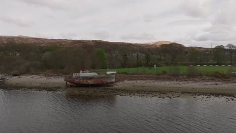 Aerial-static-shot-of-the-Corpach-Shipwreck-on-the-rocky-shores-of-Camusnagaul-Bay