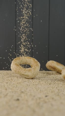 Batch-of-three-bagels-dropping-on-sesame-seeds-for-seasoning