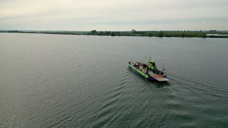 Ferry-Navega-En-Medio-Del-Río-Drone-Vuela-Detrás-Del-Ferry,-Bandera-A-Media-Asta-En-Relación-Con-El-Día-Del-Recuerdo