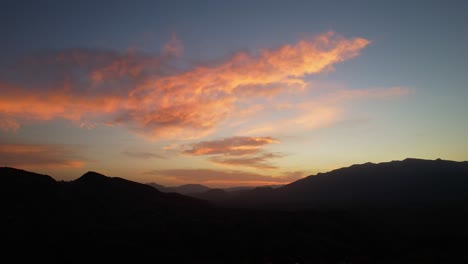 Fiery-sunrise-silhouetting-Pestera-Village-mountains,-with-vibrant-orange-clouds