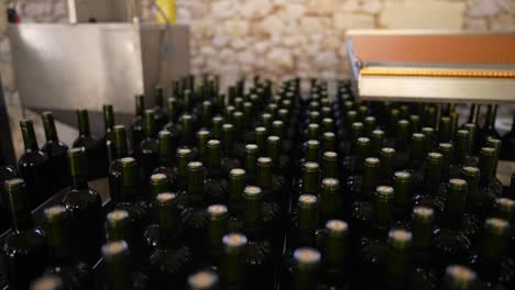 Hundreds-of-red-wine-bottles-being-moved-by-a-conveyor-belt-in-Vignonet-France,-Close-up-shot