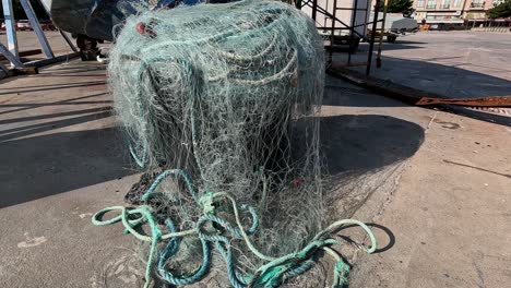 The-nylon-net-entangled-with-fishermen's-floats-piled-up-in-the-harbor-after-being-used-for-fishing-by-sailors-at-night,-natural-daylight,-shooting-back