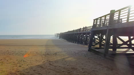 Muelle-De-Madera-Iluminado-Por-El-Sol-En-La-Playa-De-Arena-De-Saint-Jean-de-Monts-Durante-Las-Primeras-Horas-De-La-Mañana