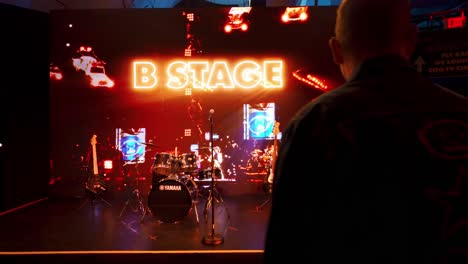 Happy-tourist-man-takes-a-photo-of-instruments-on-stage-at-U2-themed-exhibit,-Las-Vegas