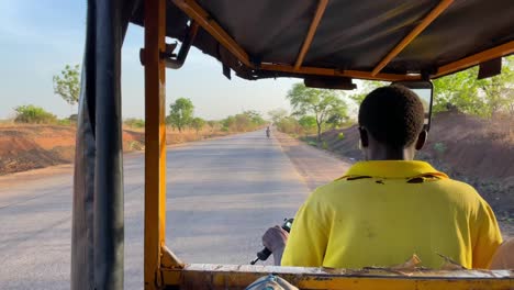 rickshaw-taxi-driving-on-road-in-Wulugu-remote-rural-village,-in-Northern-Ghana