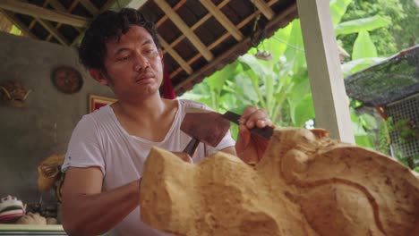 Balinese-Wood-Carver-With-Mallet-And-Chisel-Making-Traditional-Barong-Mask-In-Bali,-Indonesia