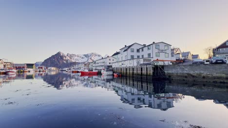 Calm-winter-morning-at-Lofoten-with-reflection-of-houses-and-boats-in-water,-clear-sky