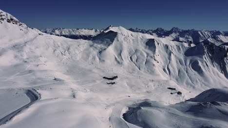 Alpine-valley-with-ski-slopes-leading-towards-ski-lift-stations