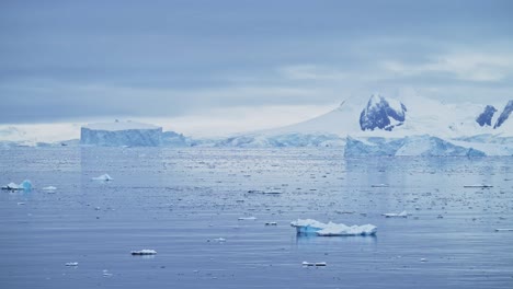 Mountains-Iceberg-and-Winter-Sea-in-Cold-Blue-Landscape-Scenery,-Antarctica-Seascape-with-Ice-and-Glacier-in-Dramatic-Beautiful-Coastal-Scene-on-Coast-on-Antarctic-Peninsula,-Moody-Blue-Atmosphric