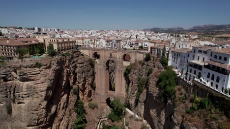 aerial-circle-shot-of-Bridge-Tajo-de-Ronda-Gorge-and-bullring-in-Ronda,-Andalusia,-Spain