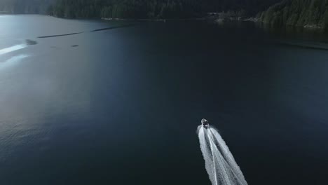 An-aerial-view-as-a-boat-gracefully-glides-through-the-waters-of-Princess-Louisa-Inlet,-BC,-Canada,-within-its-majestic-fjord,-exemplifying-the-concept-of-serene-exploration-amidst-natural-splendor