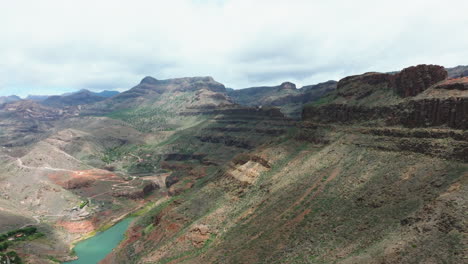 Fantastic-aerial-view-in-orbit-of-the-Sorrueda-dam-on-the-island-of-Gran-Canaria-on-a-sunny-day-with-nearby-mountains