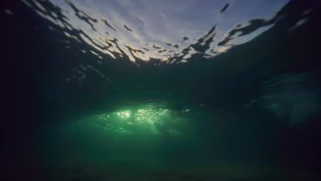 Sparkling-golden-rays-of-light-reveal-behind-underwater-breaking-wave-texture